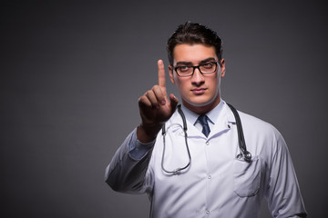 Young doctor against dark background