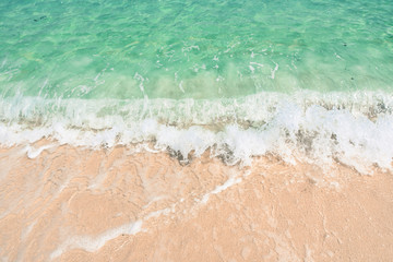 Soft wave of the tropical sea on the sandy beach. Natural summer background with copy space for background
