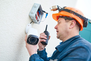 Technician worker installing video surveillance camera on wall