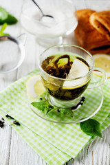 Drinks, green leaf tea with sugar, mint and lemon on a white rustic wooden background 