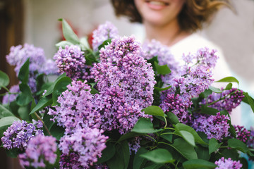 Hands of a girl with a large bouquet of lilacs