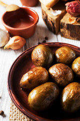 Russian and Ukrainian national cuisine, potatoes in their skin with fish, white bread, onions, garlic, cucumber and vegetable oil on a light wooden background 