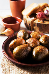 Russian and Ukrainian national cuisine, potatoes in their skin with fish, white bread, onions, garlic, cucumber and vegetable oil on a light wooden background 