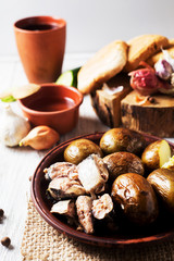 Russian and Ukrainian national cuisine, potatoes in their skin with fish, white bread, onions, garlic, cucumber and vegetable oil on a light wooden background 