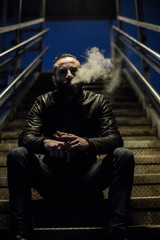 A well groomed, hipster smokes in the streets of Brooklyn. He stands alone under a streetlight during the Spring of 2017.