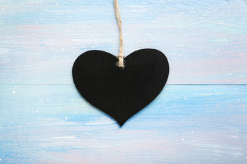 Black love heart on rope on blue wooden table