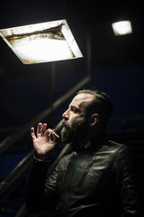 A closeup portrait of a middle aged, Egyptian man smoking alone in the streets of Brooklyn, New...