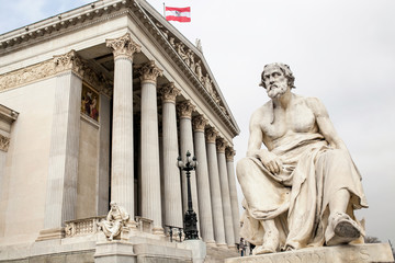 Fototapeta na wymiar main entrance of Austrian parliament building in Greek style with statues of philosophers and white columns with famous Pallas Athena fountain and in Vienna