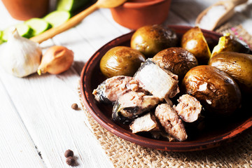 Russian and Ukrainian national cuisine, potatoes in their skin with fish, white bread, onions, garlic, cucumber and vegetable oil on a light wooden background 