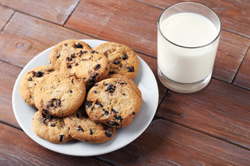 Chocolate chip cookies with glass of milk on brown wooden table
