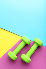 Green dumbbells on colorful background