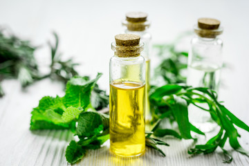 organic oil in bottle with rosemary and mint on light table background