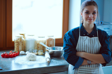 Young woman standing by the stove in the kitchen