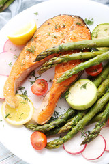 Steak of salmon with asparagus and vegetables on white wooden table
