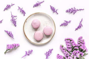 lady morning with macaroons and mauve flowers white desk background top view pattern