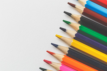 Colourful pencils on white paper background