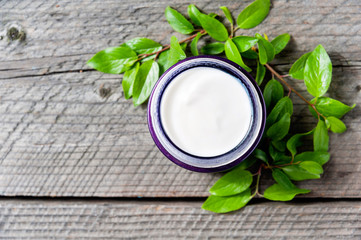 Jar of moisturizing facial cream with leaves top view