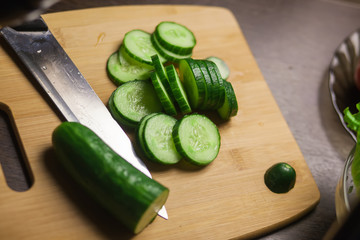 Parts of a cut cucumber on a cutting board and a knife