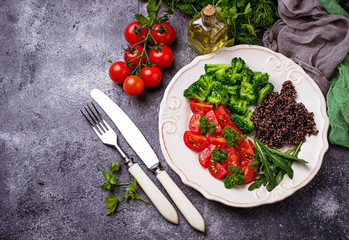 Salad with black quinoa, cherry tomatoes, broccoli and arugula