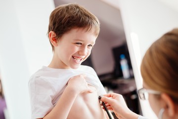 Little smiling boy child is examining by a doctor