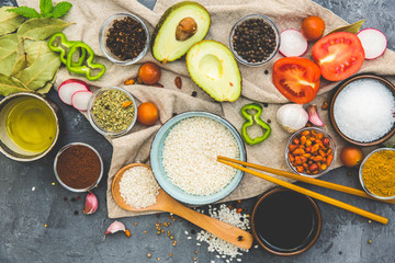 Rice, Spices and Vegetables over dark rustic background. Vegetarian cooking concept. Asian or Indian food