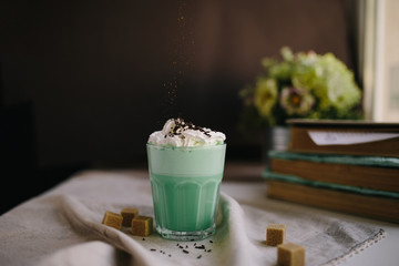 Green mint coffee with with cream and colorful decoration on dark background. Milk shake, cocktaill, frappuccino.  Unicorn coffee, unicorn food.