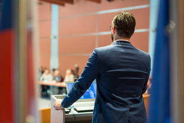 Speaker giving a talk on corporate Business Conference. Audience at the conference hall. Business and Entrepreneurship event.