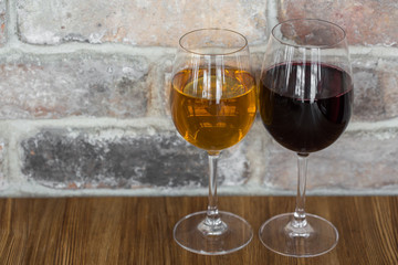 Glasses of red and white wine on rustic brick wall background with copy space