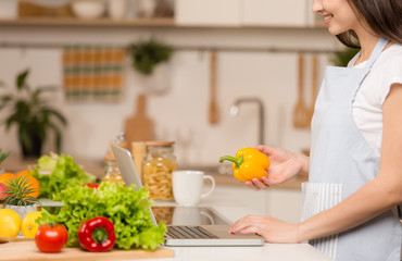 Young Woman standing in kitchen with tablet computer and looking recipes. Close-up.