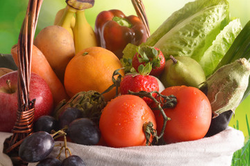 Fruits and vegetables in a wicker basket with green background