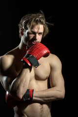 Boxer thinks or dreams. Portrait of boxer posing in studio in red boxing gloves.