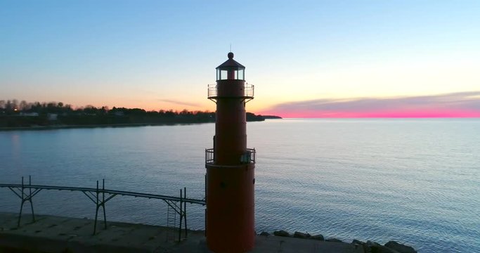 Scenic aerial flyby of Lake Michigan lighthouse and harbor at twilight, Algoma, Wisconsin