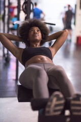 Obraz na płótnie Canvas black woman doing sit ups at the gym