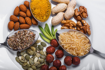 Assorted nuts in white bowl, plate on wooden surface.  peanuts, almonds, hazelnuts, pumpkin seeds, walnuts, rice , buckwheat. Top view with copy space