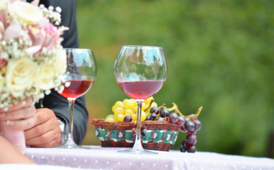 Groom and bride sitting at the table with glasses of red wine in background