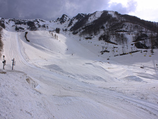 Fototapeta na wymiar Snowy empty mountain ski gentle slope. Rosa Khutor, Sochi, Russia.