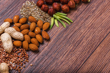 Assorted nuts on wooden surface. peanuts, almonds, hazelnuts, pumpkin seeds, walnuts, rice, buckwheat. Top view with copy space.