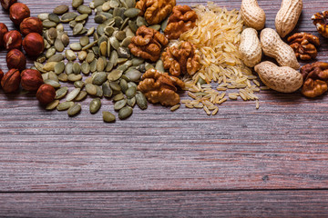 Assorted nuts on wooden surface. peanuts, almonds, hazelnuts, pumpkin seeds, walnuts, rice, buckwheat. Top view with copy space.