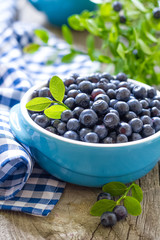 Fresh blueberries with leaves on wooden background