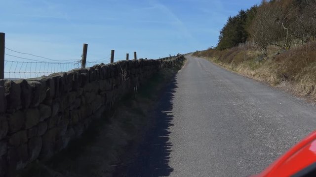 Handheld camera shot out of car window while driving up the hill in rural England