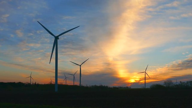 Giant wind turbines backlit by the dawn sky.
