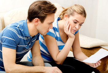 Worried couple after calculating bills sitting at home