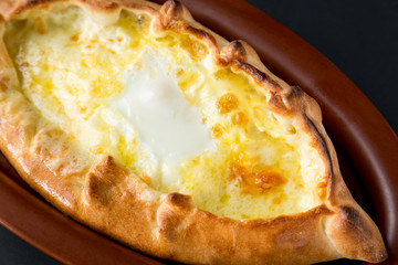 Adjarian khachapuri with eggs close up on black background