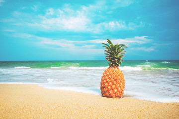 Naklejka premium Ripe pineapples on the sandy tropical beach with clear blue sky. Leisure in summer and Summer vacation concept. vintage color tone.