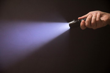 Black flashlight in male''s hand from right top corner isolated on black background