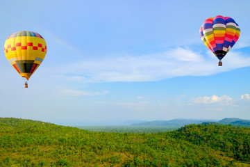 Naklejka premium Hot-air Balloon floating in the sky near a rainbow over the mountains. landscape background
