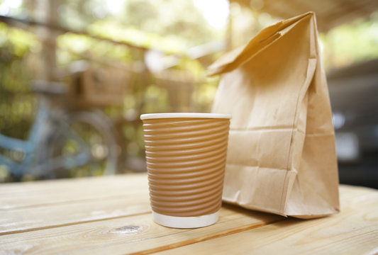 cup coffee and bread in paper bag.