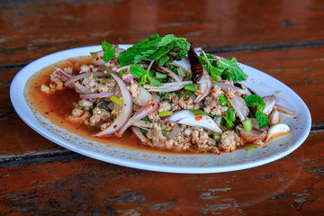 Spicy minced pork salad, minced pork mash with spicy, Thai food style. on the wooden table.