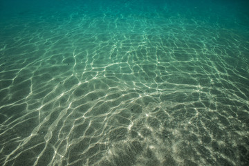 Underwater bottom with caustic on sand on background. Tropical ocean water design abstract template
