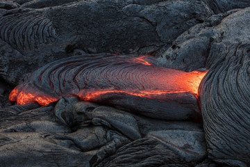 Molten magma red hot lava flowing on cold lavafiled in grey colored texture of volcanic background